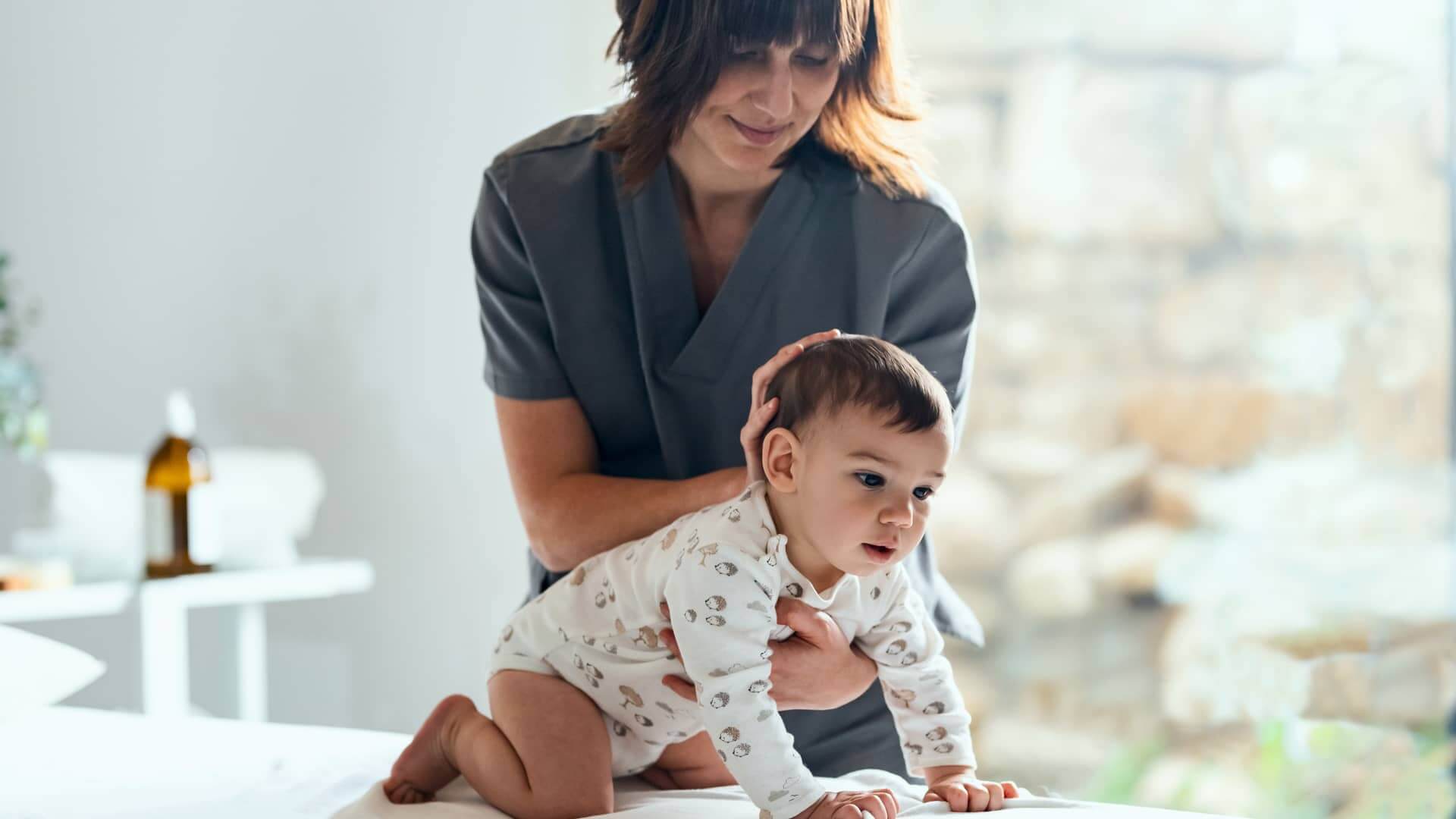 Madre aprendiendo ejercicios de fisioterapia para su bebé