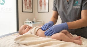 Fisioterapeuta pediátrico de TMKine realizando un masaje abdominal suave para aliviar el cólico del lactante y mejorar el tránsito intestinal.